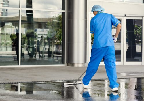 Professional industrial cleaner in protective uniform cleaning floor